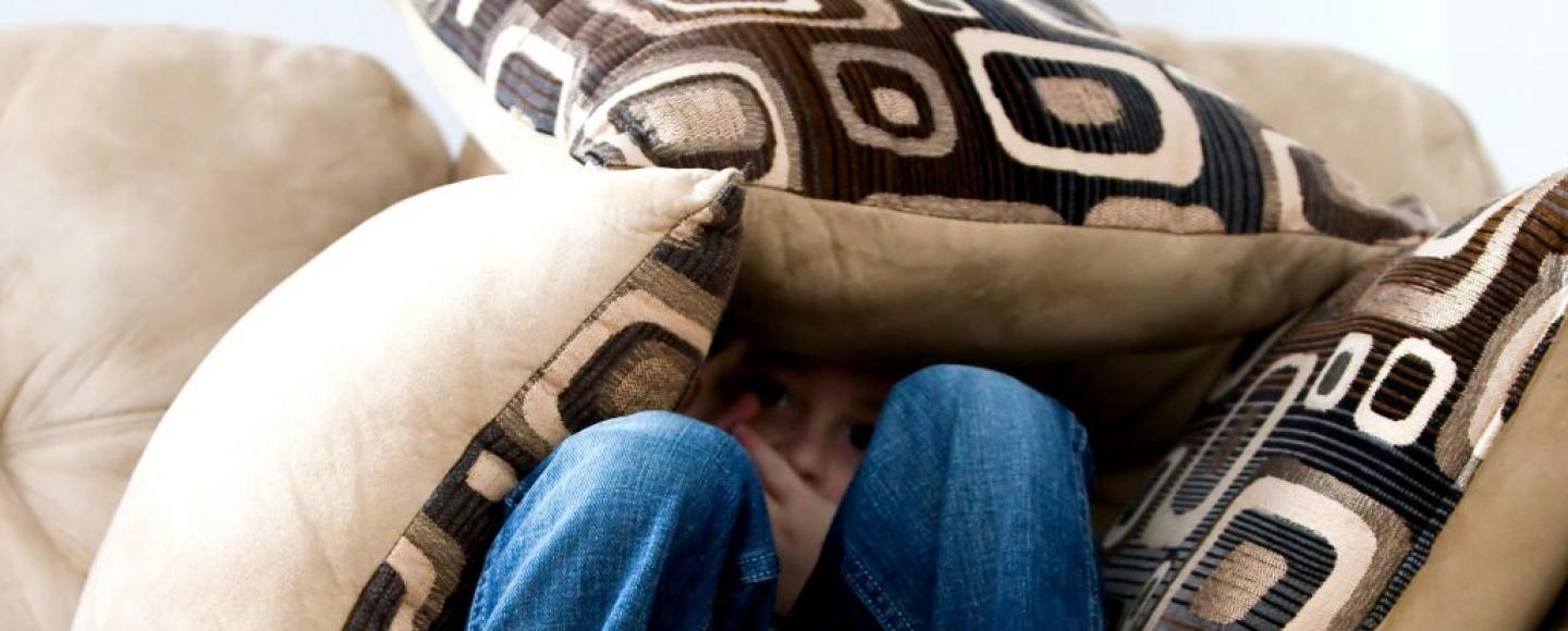 image of boy hiding under pillows