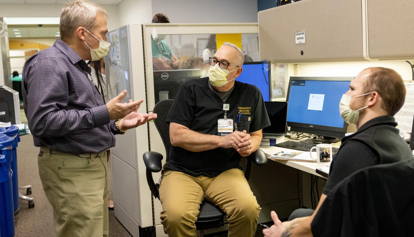 Dr. Gerry Clancy confers with colleagues in the Emergency Department, including social worker Lance Clemsen (left) on Tuesday, December 6, 2022. Clancy hosts a podcast Rounding@Iowa as well as a new program called THRIVE that offers leadership skills sessions to early-career faculty.