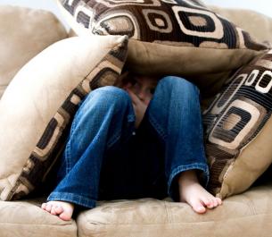 image of boy hiding under pillows