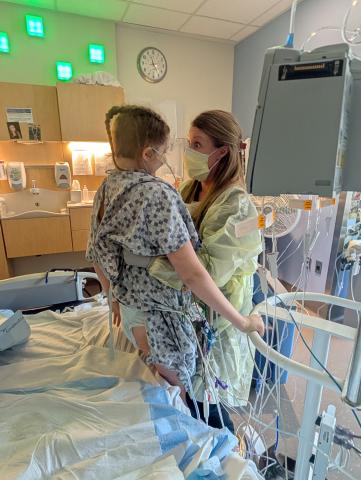 Payten stands with assist from PICU PT Bri